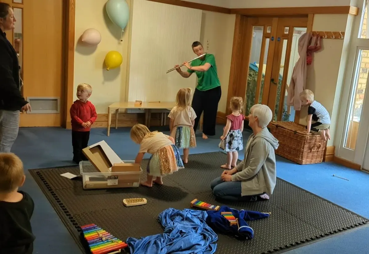 Kate plays flute for a group of children.