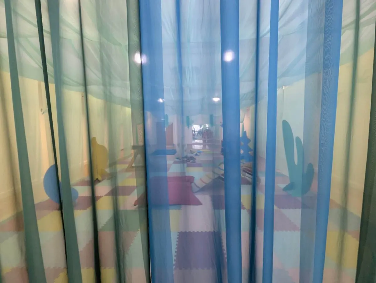 Looking through soft blue voile curtains into the Cocoon playspace.