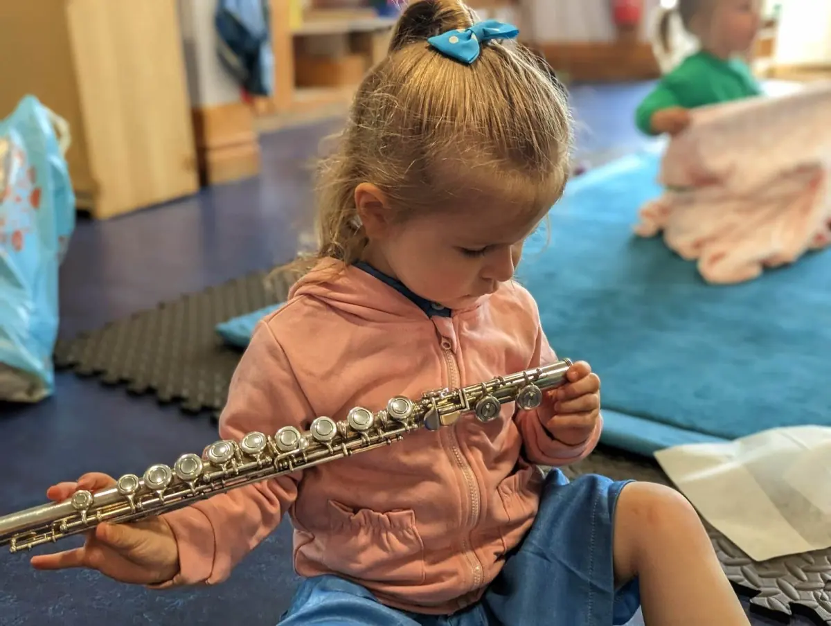 A young girl holds and studies the flute carefully.